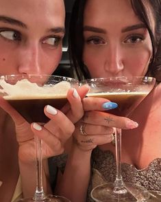 two women holding up wine glasses in front of their faces