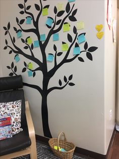 a tree with notes on it is next to a chair in the room that's decorated with post - it notes