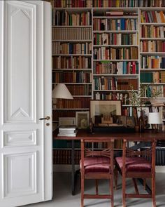 a room filled with lots of books next to a white door in front of a book shelf