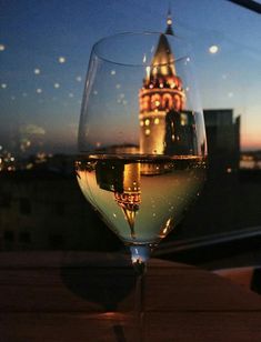 a glass of wine sitting on top of a wooden table next to a tall building