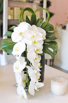 a vase filled with white flowers sitting on top of a table next to a candle