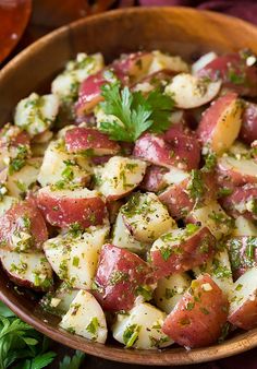 a wooden bowl filled with potatoes and herbs