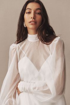 a woman wearing a white dress with long sleeves and an asymmetrical neckline