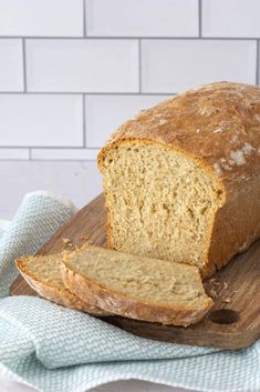 a loaf of bread sitting on top of a wooden cutting board next to a blue and white towel