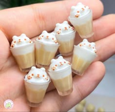 there are small cups with whipped cream on them in someone's hand and one is holding it