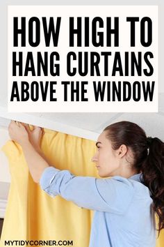 a woman hanging curtains with the words how high to hang curtains above the window