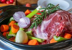 meat and vegetables in a slow cooker ready to be cooked for the dinner guests