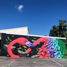 a large colorful bird painted on the side of a building next to a parking lot