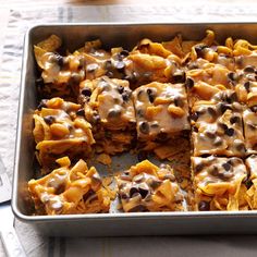 a baking pan filled with cookies and chocolate chips covered in frosting on top of a table