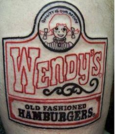 an old fashioned hamburger label tattoo on the back of a man's leg,