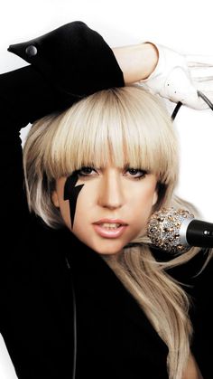 lady with black and white face paint holding a microphone to her head while posing for the camera