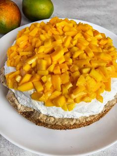 a white plate topped with a piece of cake covered in mangos and whipped cream