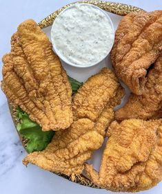 fried food on a plate with dipping sauce in the middle and lettuce leaves next to it