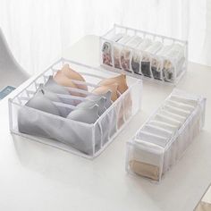 three clear plastic drawers on a desk with shoes and bras in the bottom drawer