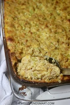 a casserole dish with a spoon in it on top of a white cloth