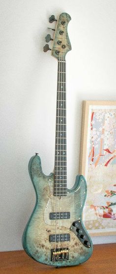 an electric bass guitar sitting on top of a wooden table next to a framed photograph