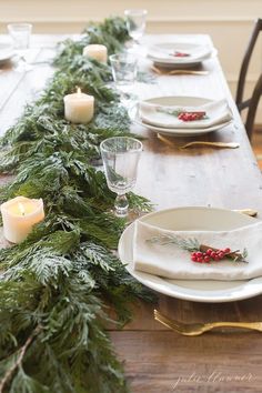 the table is set with candles and evergreen garland