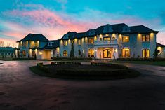 a large white house with lots of windows and lights on it's front entrance