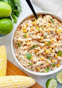 a bowl filled with rice next to corn on the cob and limes