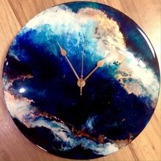 a clock that is sitting on top of a wooden table with blue and gold paint