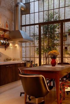 a kitchen with a table and chairs in front of a window filled with potted plants