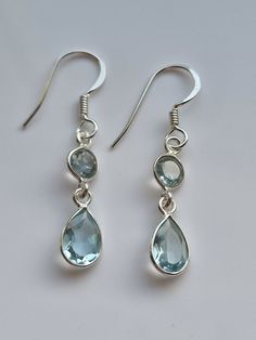 Behold the captivating allure of our blue topaz crystal earrings, a dazzling duo of celestial elegance. Crafted with meticulous precision, these earrings feature a perfect pairing of a lustrous round blue topaz crystal and a gracefully suspended teardrop-shaped blue topaz crystal, both delicately embraced by polished sterling silver settings. The round crystal, like a radiant full moon, enchants with its ethereal blue hue, while the teardrop crystal evokes a sense of timeless grace, shimmering w Cute Blue Earrings, Blue Earrings Aesthetic, Blue Topaz Crystal, Ethereal Blue, Pretty Jewelry Necklaces, Topaz Crystal, Blue Crystal Earrings, Blue Dangle Earrings, Sagittarius Capricorn