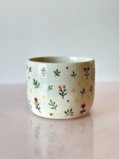 a white bowl with flowers painted on the side and gold flecks around it