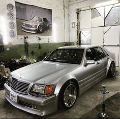 a silver car parked in a garage next to a wall with pictures hanging on it