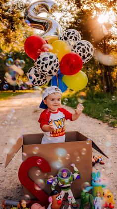 a little boy that is sitting in a box with some balloons on top of it