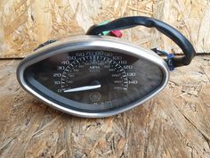 a speedometer sitting on top of a wooden table next to a piece of wood