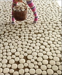 a woman in striped socks holding a basket full of white rocks on top of a rug