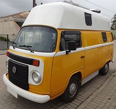 a yellow and white van parked on the side of a road next to a building