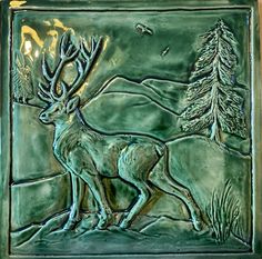 a ceramic tile with a deer and pine trees