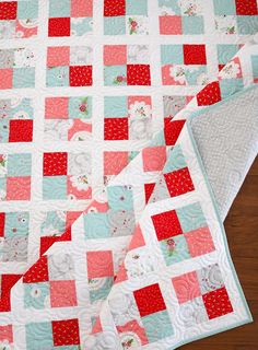 a red and blue quilt is laying on a wooden floor next to a piece of cloth