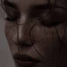 a woman's face with freckles on her skin and hair blowing in the wind