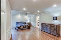 a large bedroom with hardwood floors and white walls, along with a blue bed in the middle