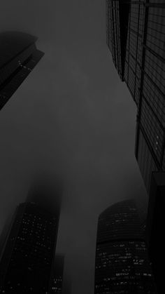 black and white photograph of skyscrapers in the city at night with foggy sky