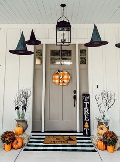 a front porch decorated for halloween with pumpkins and other decorations on the door mat