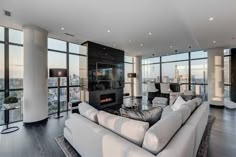 a living room filled with white furniture and tall windows overlooking the cityscape in the distance