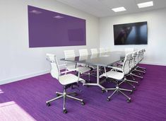 an empty conference room with purple carpeting and white chairs in front of a flat screen tv