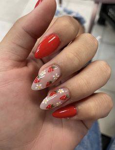 a woman's hand with some red and white nail polishes on her nails