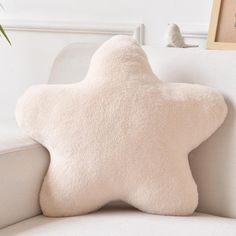 a star shaped pillow sitting on top of a white couch next to a potted plant