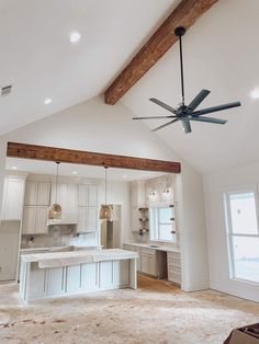 a ceiling fan is hanging in the middle of a room with white cabinets and counter tops