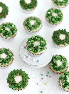 cupcakes decorated in green and white frosting with holly wreath decorations on top