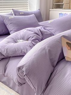 a bed with purple comforters and pillows