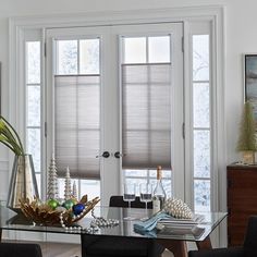 a dining room table with chairs and vases on top of it next to two windows