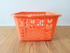 an orange plastic basket sitting on top of a wooden floor