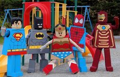 some legos are standing next to each other in front of a play set with superman, spiderman and iron man