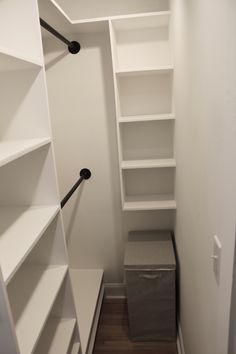 an empty walk in closet with white shelving