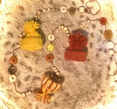 three knitted hats sitting on top of a fur covered floor next to buttons and beads